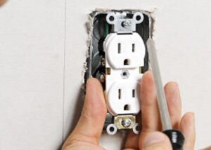 Eletctrical troubleshooting.A set of hands working on a electrical outlet with a screwdriver